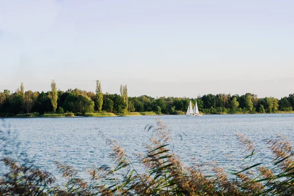 Sailing boat on a calm lake with reflection in the water. Serene scene landscape. Horizontal photograph.