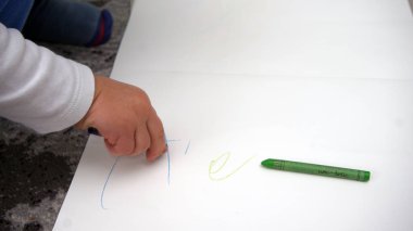 Çocuk yere mum boya çizmeyi öğreniyor.