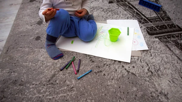 A criança aprende a desenhar lápis de cera no chão — Fotografia de Stock