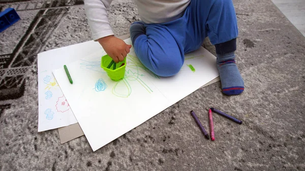 Ребенок учится рисовать восковые карандаши на полу — стоковое фото