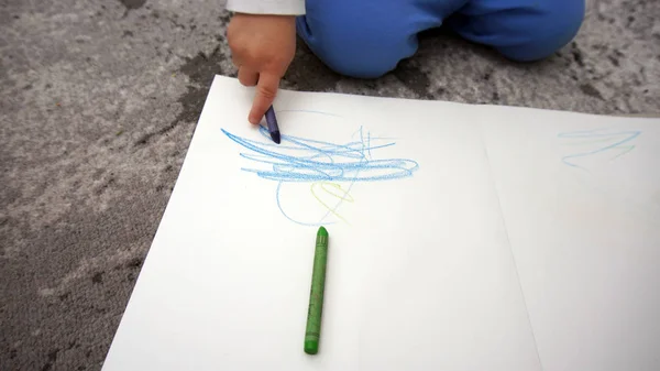 Ребенок учится рисовать восковые карандаши на полу — стоковое фото