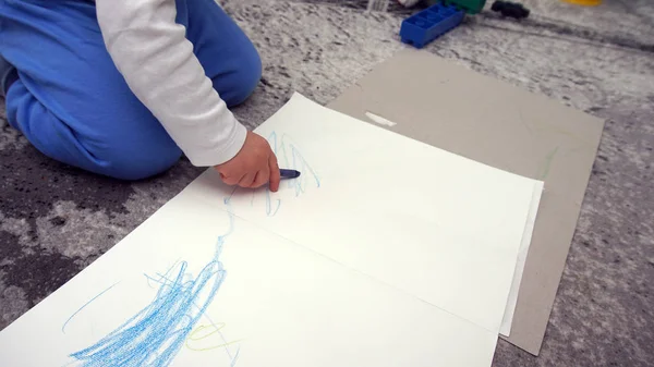 A gyerek megtanulja, hogyan rajzoljon zsírkrétát a padlóra. — Stock Fotó