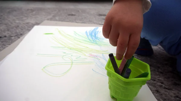 A criança aprende a desenhar lápis de cera no chão — Fotografia de Stock