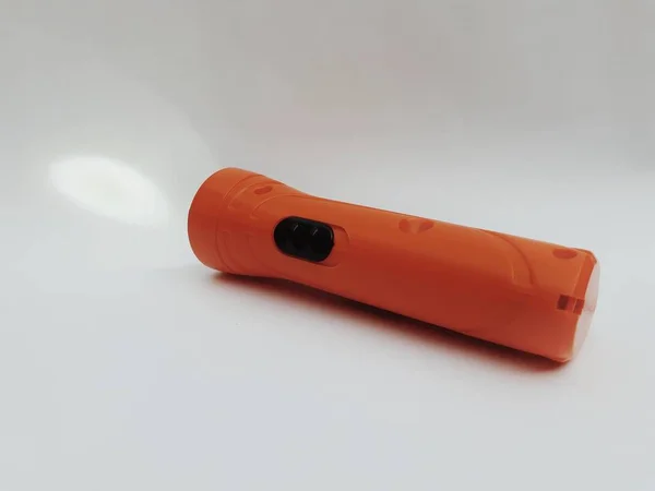 Small orange colour rechargeable torchlight in on mode  isolated on grey background. Easy to carry torchlight image