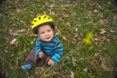 Sevimli gülümseyen bebek çocuk sonbahar parkta oturan kask ile
