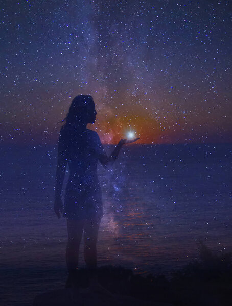 Ночное небо, полное звезд и силуэт стоящей девушки со звездой в руке. Единство человека и вселенной
. 