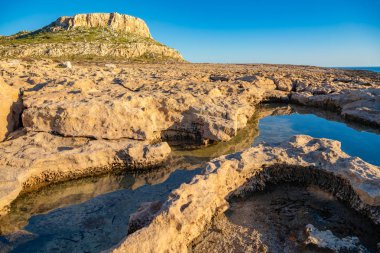Kayalıklar sudaki yansıması ile güzel manzara. Gün batımında Ayia Napa kıyı şeridi. Cape Greco Ulusal Forest Park, Kıbrıs.