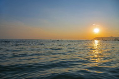 Muhteşem deniz manzarası. Güzel gün batımı dalgalar açıktı. Ufukta dağların ve gemilerin siluetleri. Porto Di Marina Di Pisa, İtalya.