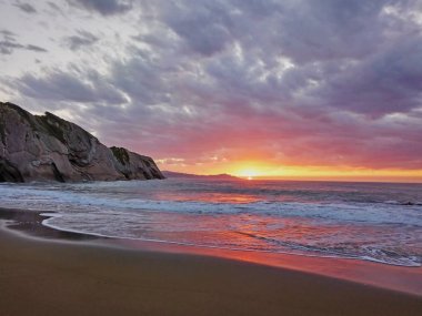 Muhteşem deniz manzarası. Güzel gün batımı dalgalar açıktı. Ufukta dağların ve gemilerin siluetleri. Itzurun plajı, Gipuzkoa sahilinde Zumaia flysch, İspanya.