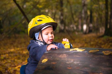 Sonbahar parkında kasklı, gülümseyen tatlı çocuk.
