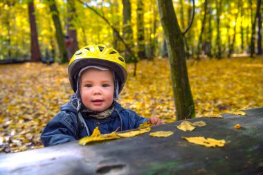 Sonbahar parkında kasklı, gülümseyen tatlı çocuk.