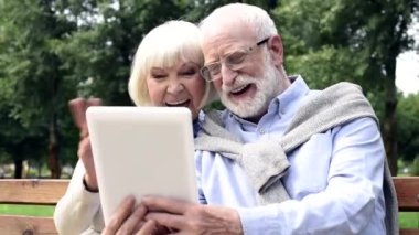 tablet kullanma ve Park görüntülü arama sırasında el sallayarak kıdemli mutlu çift