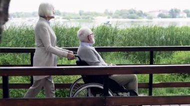 üst düzey karısı kocası river Park yakınındaki yolda tekerlekli sandalye üzerinde iterek yan görünüm