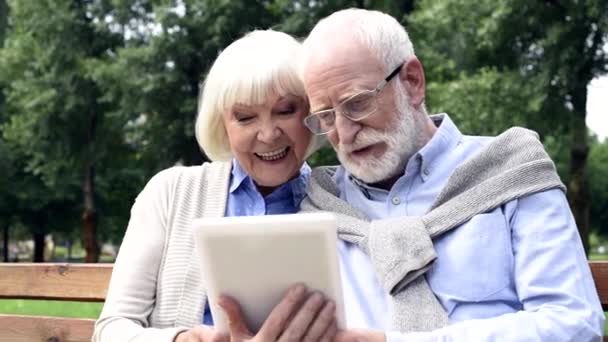 Feliz Pareja Ancianos Hablando Utilizando Tableta Banco Parque — Vídeos de Stock