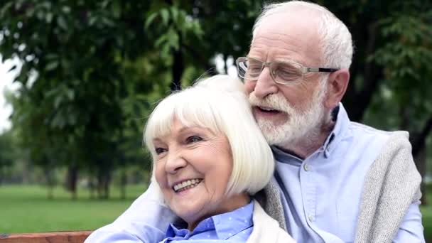 Senior Couple Hugging Bench Talking Looking Away Park — Stock Video