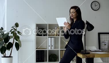 gülümseyen işkadını modern ofiste masa yakınındaki dijital tablet kullanma 