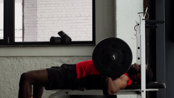 アフリカ系アメリカ人の若いスポーツマンがスローモーションでジムでバーベルを持ち上げる — ストック動画