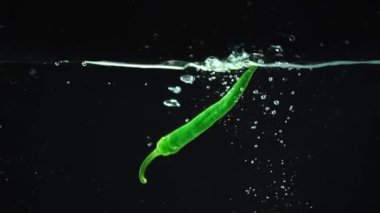 stüdyo çekimi renkli yeşil ve kırmızı biber ile su sıçramalarına düşen siyah arka plan üzerine açık suya biber