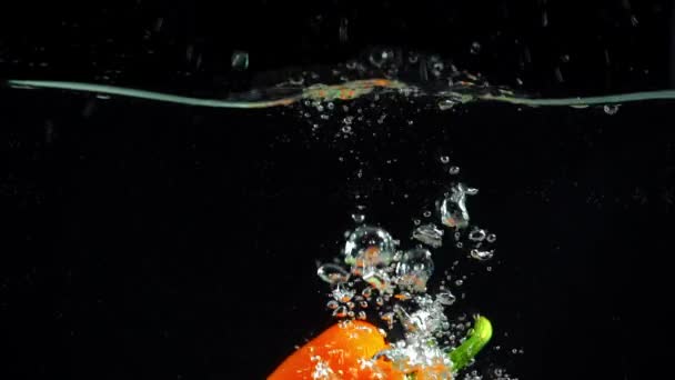 Pimiento Naranja Brillante Inmersión Agua Clara Sobre Fondo Negro — Vídeo de stock