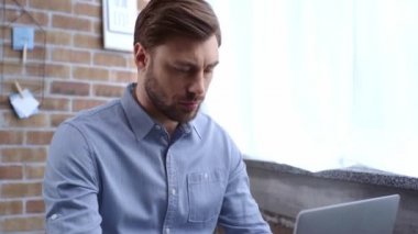 Dizüstü bilgisayar kullanarak ve işyerinde kahve içme mavi gömlekli yoğun iş adamı