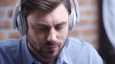 Müzik dinleme ve beyaz kulaklık dokunmadan kafa sallayarak saati olan genç adam