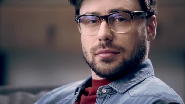 Curious Man Denim Shirt Glasses Turning Camera Blinking Dark Background — Stock Video