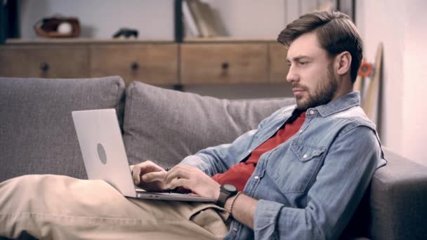 Frilansare Jeansskjorta Liggande Soffan Med Laptop Skriva Tangentbord Och Blinkar — Stockvideo