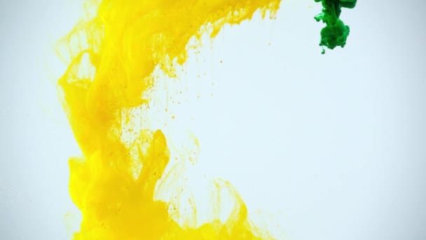 slow motion shoot of green and yellow paints dissolving in water on grey background