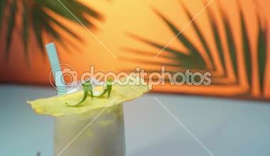 Yeşil palmiye yaprakları ile turuncu arka plan üzerinde dönen dekorasyon ile pina colada ıslak cam kokteyl görünümünü kadar yakın