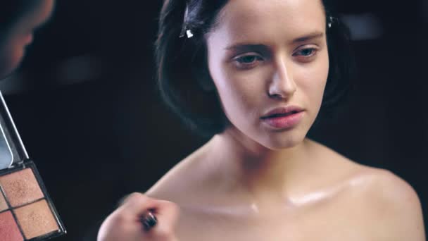 Makeup Artist Håller Palett Och Tillämpa Skimrande Highlighter Modell Nyckelbenen — Stockvideo