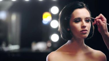 arka planda bokeh ışıkları ile model kaş fırçalama makyaj sanatçısı kısmi görünümü