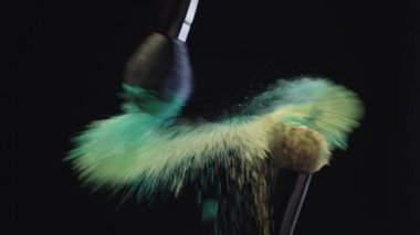 iki kozmetik fırçalar dokunmadan ve sarı ve yeşil holi boyalar sıçrama yapma yavaş hareket ateş