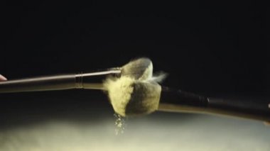 iki kozmetik fırçalar dokunmadan yavaş hareket ateş ve sarı holi boya sıçrama yapma ve sonra toz yavaş yavaş aşağı düşen