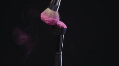 dokunmadan ve pembe holi boya sıçramaları yapma iki kozmetik fırçalar yavaş hareket çekimi