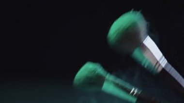 isabet ve siyah arka plan üzerinde yeşil holi boya sıçramaları yapma kozmetik fırçalar yavaş hareket ateş