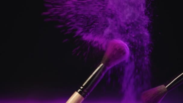 カラフルな紫色のホリパウダーをこすり 散乱する2つの化粧品ブラシのスローモーションシュート — ストック動画