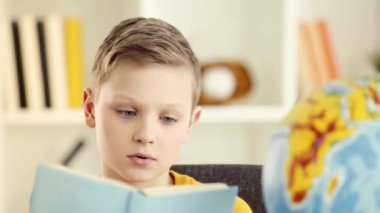 sevimli okul çocuğu okuma seçici odak, baş kitap koyarak ve evde iç çekme 