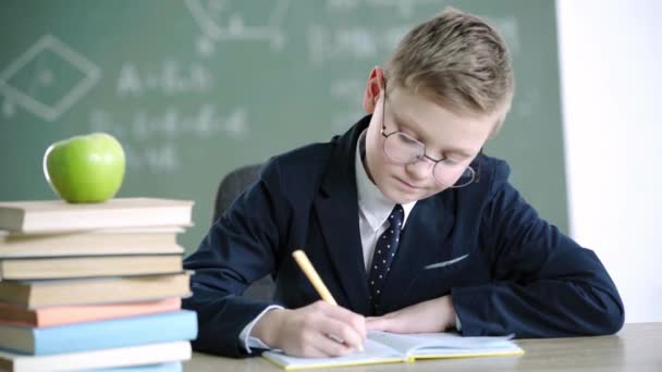 Menino Escola Triste Óculos Escrevendo Notebook Perto Livros Maçã Enquanto — Vídeo de Stock