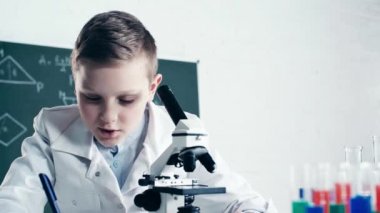 sınıf sıvı ile test tüpleri yakın mikroskop ile çocuk yazma ve bakarak seçici odak 