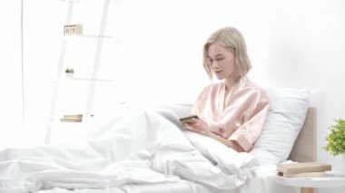 sarışın kız dijital tablet kullanarak, kredi kartı alarak ve yatak odasında online alışveriş yaparken gülümseyerek