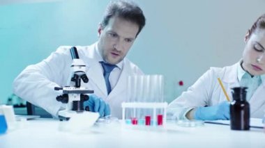 güzel doktor sonuçları yazarken test tüpünden kırmızı sıvı alarak yakışıklı bilim adamı