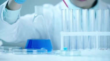 kırmızı sıvı ve petri kapları ile cam şişesi yakın test tüpü ne kırmızı sıvı ekleyerek bilim adamlarının kırpılmış görünümü