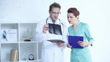 yakışıklı doktor ve güzel hemşire panoları ile ayakta ve x-ray tanısı bakarken konuşurken 