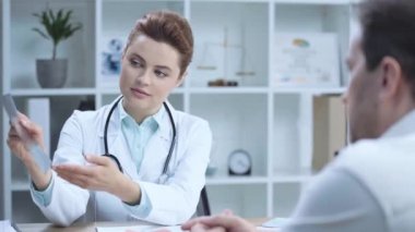 meslektaşıyla konuşurken x-ray tanısında elle işaret eden güzel doktorun seçici odağı 