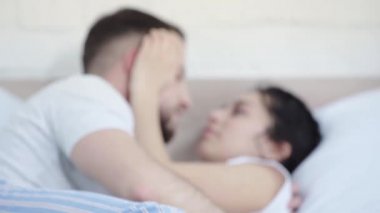 yatakta yatarken çekici kadının burnunu ve elini öpen mutlu erkeğin seçici odak 