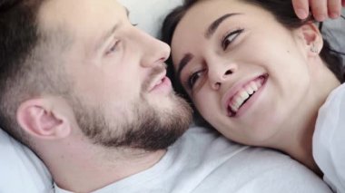 öpüşürken ve yatakta yatarken neşeli kadının yüzüne ve saçına dokunan mutlu erkeğin yakın 