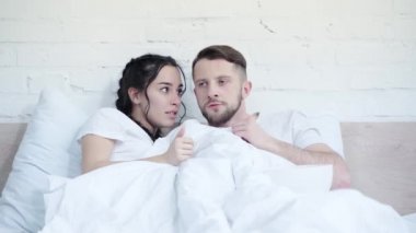 Yakışıklı erkek arkadaşın yanında film izleyen korkmuş kadın yatak odasında patlamış mısır yiyor. 