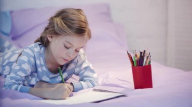 pijama yatakta yatan, çizim ve renk kalemleri değişen sevimli çocuk odaklı