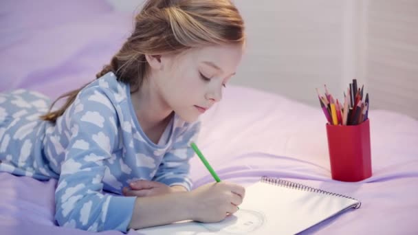 Carino Bambino Pigiama Sdraiato Sul Letto Disegno Con Matite Colore — Video Stock