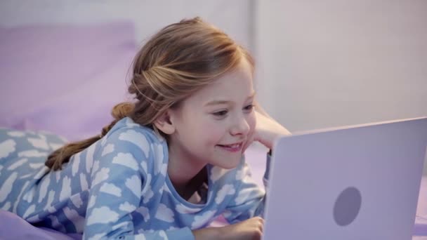 Ребенок Подросток Пижаме Лежит Кровати Помощью Ноутбука Подпирает Лицо Улыбкой — стоковое видео